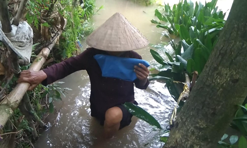 Người dân lội qua đoạn đường sạt lở.