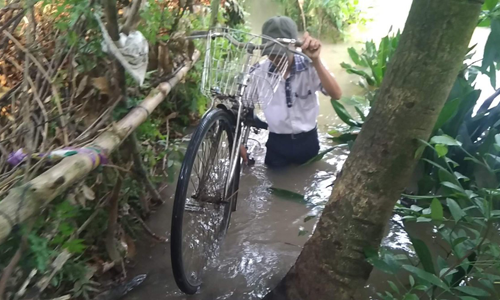 Học sinh đi học phải lội qua đoạn đường sạt lở nước ngập gần tới thắt lưng.