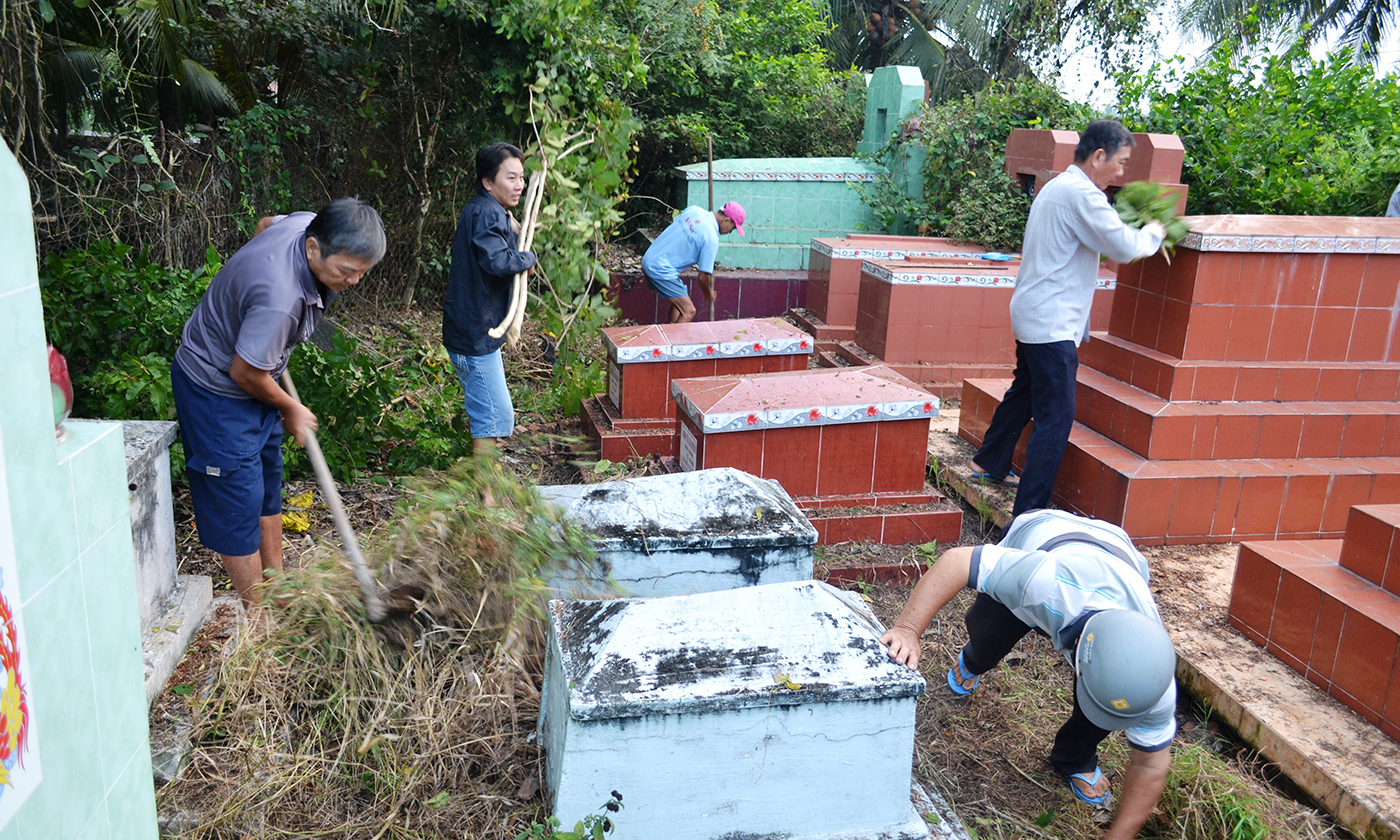 con cháu chặt cỏ vệ sinh phần mộ ông bà