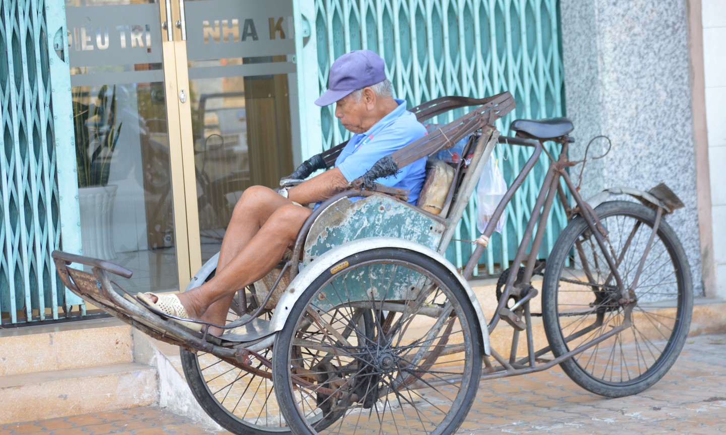 Ông lão tranh thủ chợp mắt cùng với chiếc xe xích lô.