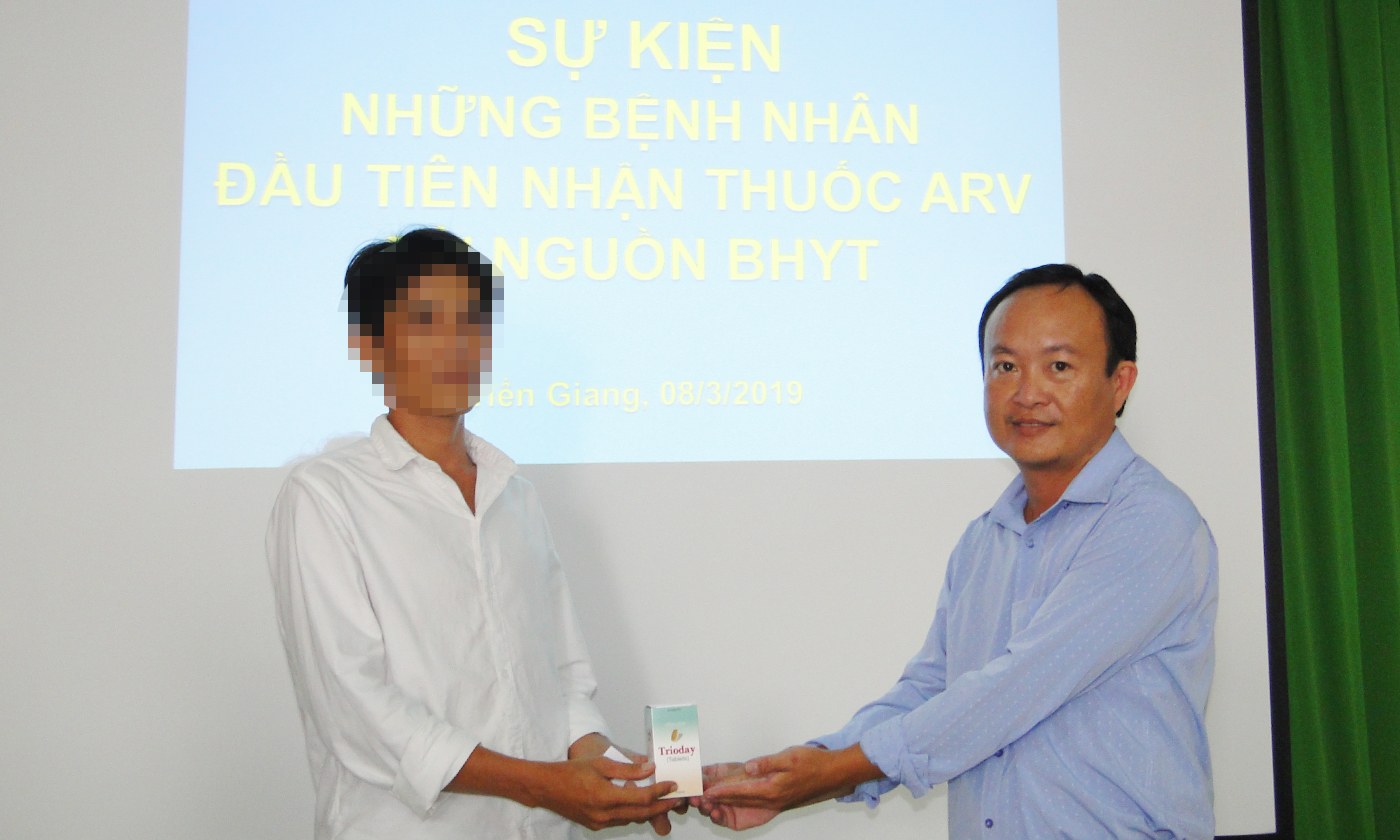 Đại diện Trung tâm kiểm soát bệnh tật (bên phải) trao thuốc ARV từ quỹ BHYT cho bệnh nhân