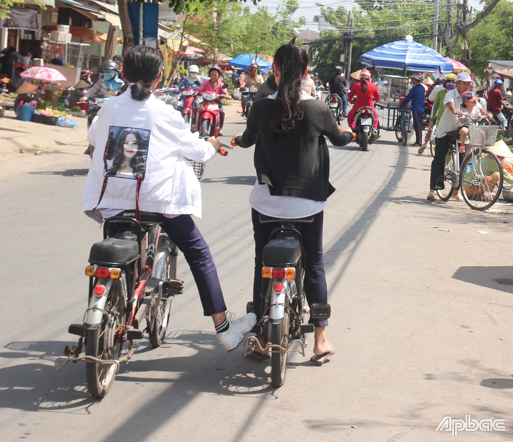Học sinh kéo, đẩy xe đạp điện tại chợ Cũ, (phường 8, TP. Mỹ Tho).