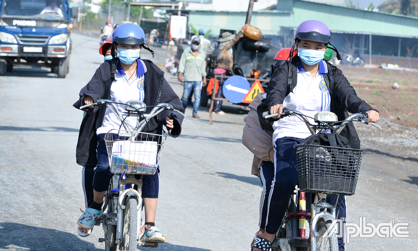 Học sinh đội mũ bảo hiểm khi điều khiển xe đạp điện, nhưng quên cài quai mũ bảo hiểm. Ảnh chụp tại huyện Tân Phú Đông.