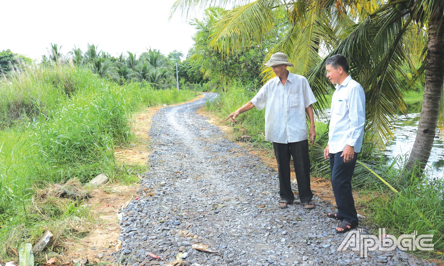 Ông Tươi (bên trái) trên tuyến đường số 2 (ấp 6, xã Phú An) do ông vận động kinh phí, ngày công nâng cấp.