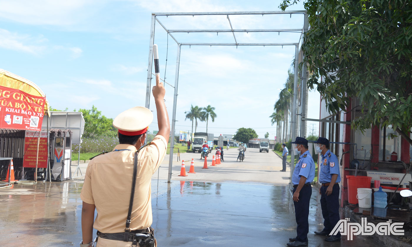 Lực lượng chức năng điều tiết xe ra vào đi qua hệ thống phun sương khử khuẩn tại chổng chính KCN Long Giang.