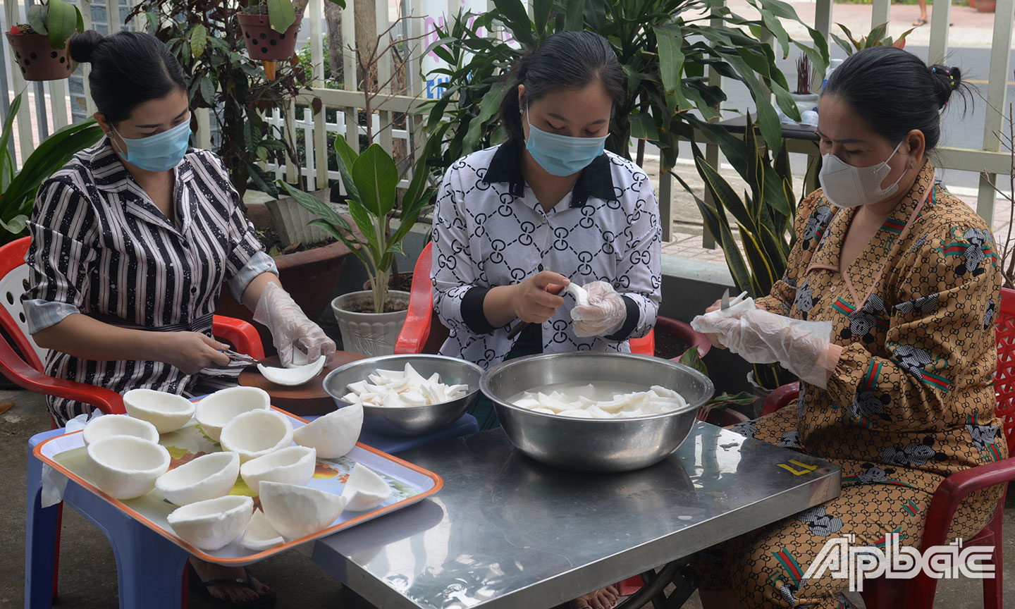 Chị Tuyến (bìa trái), phường 4, TX. Cai Lậy, sơ chế mứt dừa non hình bông cho ngày tết.