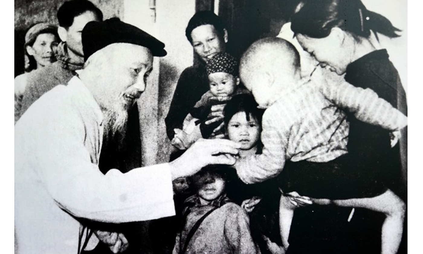 Bác Hồ chia quà Tết cho các cháu nhỏ ở Hợp tác xã Khe Cát, huyện Yên Hưng, tỉnh Quảng Ninh ngày 2-2-1965. Ảnh: Bảo tàng Hồ Chí Minh. 