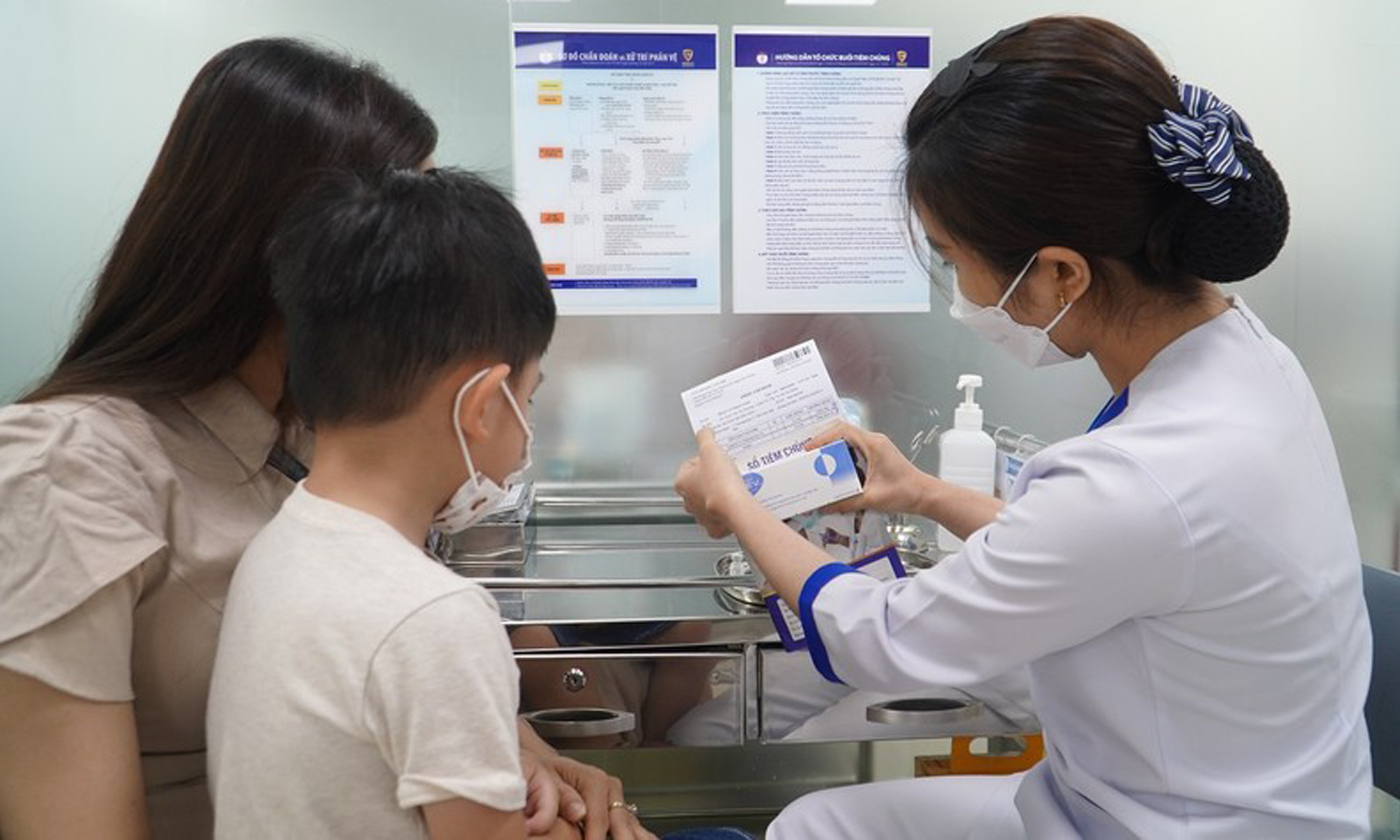 Nhân viên tiêm chủng rà soát lại thông tin người tiêm, loại vaccine, hạn sử dụng cho mẹ của trẻ.