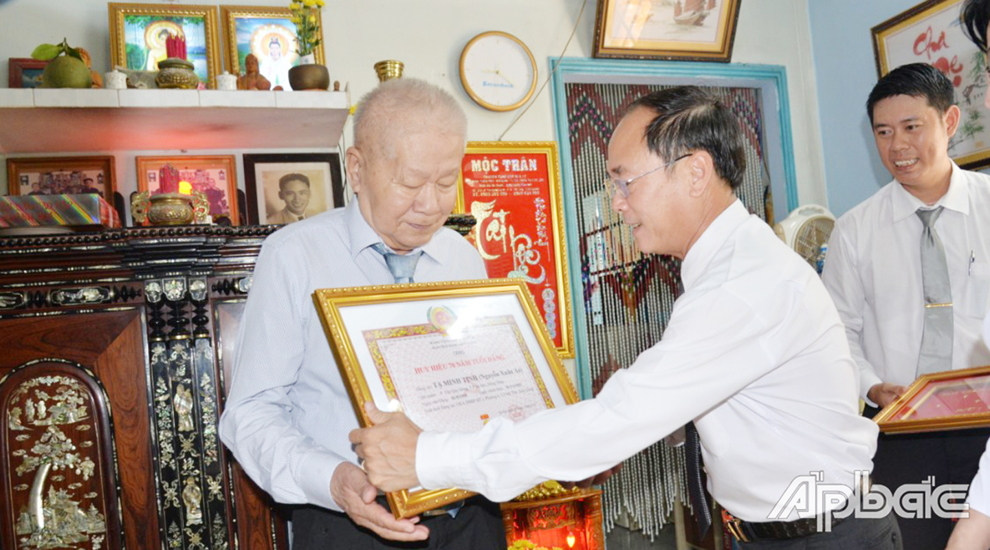 Đồng chí Trần Kim Trát, Ủy viên Thường vụ Tỉnh ủy, Bí thư Thành ủy Mỹ Tho đến tận gia đình trao tặng Huy hiệu 70 năm tuổi đảng cho đồng chí Tạ Minh Tịnh.