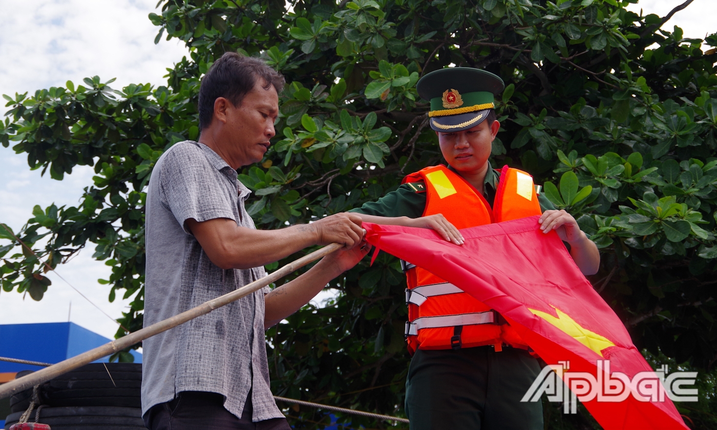 Trung úy Đặng Quốc Cường tuyên truyền IUU và tặng cờ cho ngư dân.