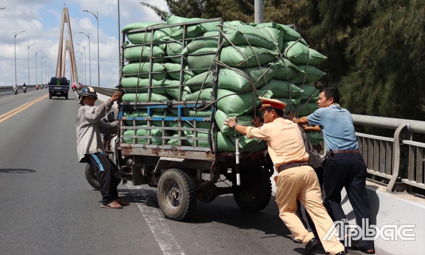 ực lượng Cảnh sát giao thông hỗ trợ người dân đưa phương tiện hư hỏng về lại chân cầu Rạch Miễu, bảo đảm an toàn giao thông trên cầu. Ảnh Lê Hoài