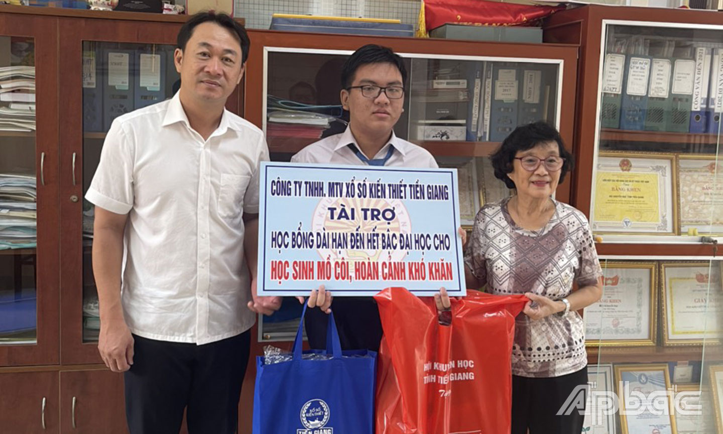 Phó Giám đốc Công ty TNHH MTV Xổ số kiến thiết Tiền Giang Trần Văn Giang và Chủ tịch Hội Khuyến học tỉnh Đồng Thị Bạch Tuyết trao bảng tài trợ học bổng cho em Đỗ Quang Trung.