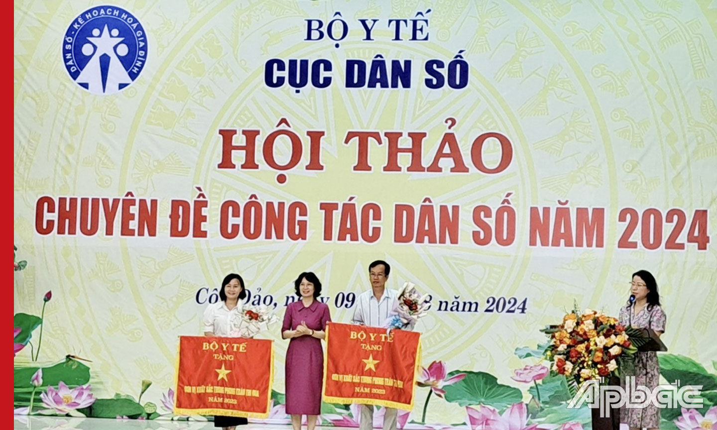 Bác sĩ chuyên khoa 2 Nguyễn Thành Sang, Chi cục trưởng Chi cục Dân số tỉnh Tiền Giang (bên phải) đón nhận Cờ thi đua từ Thứ trưởng Bộ Y tế.