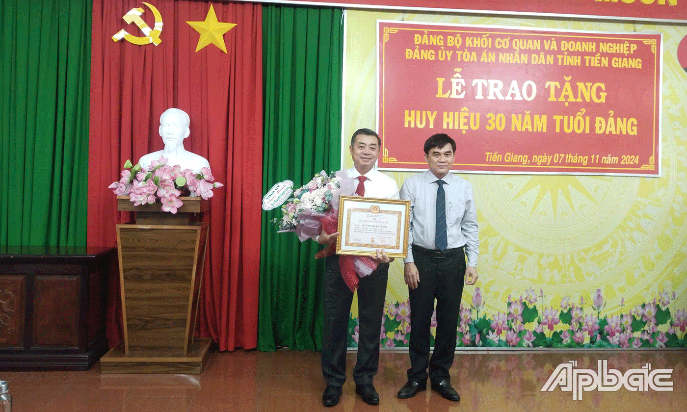 Đồng chí Nguyễn Văn Mười trao Huy hiệu 30 năm tuổi Đảng cho đồng chí Huỳnh Xuân Long.