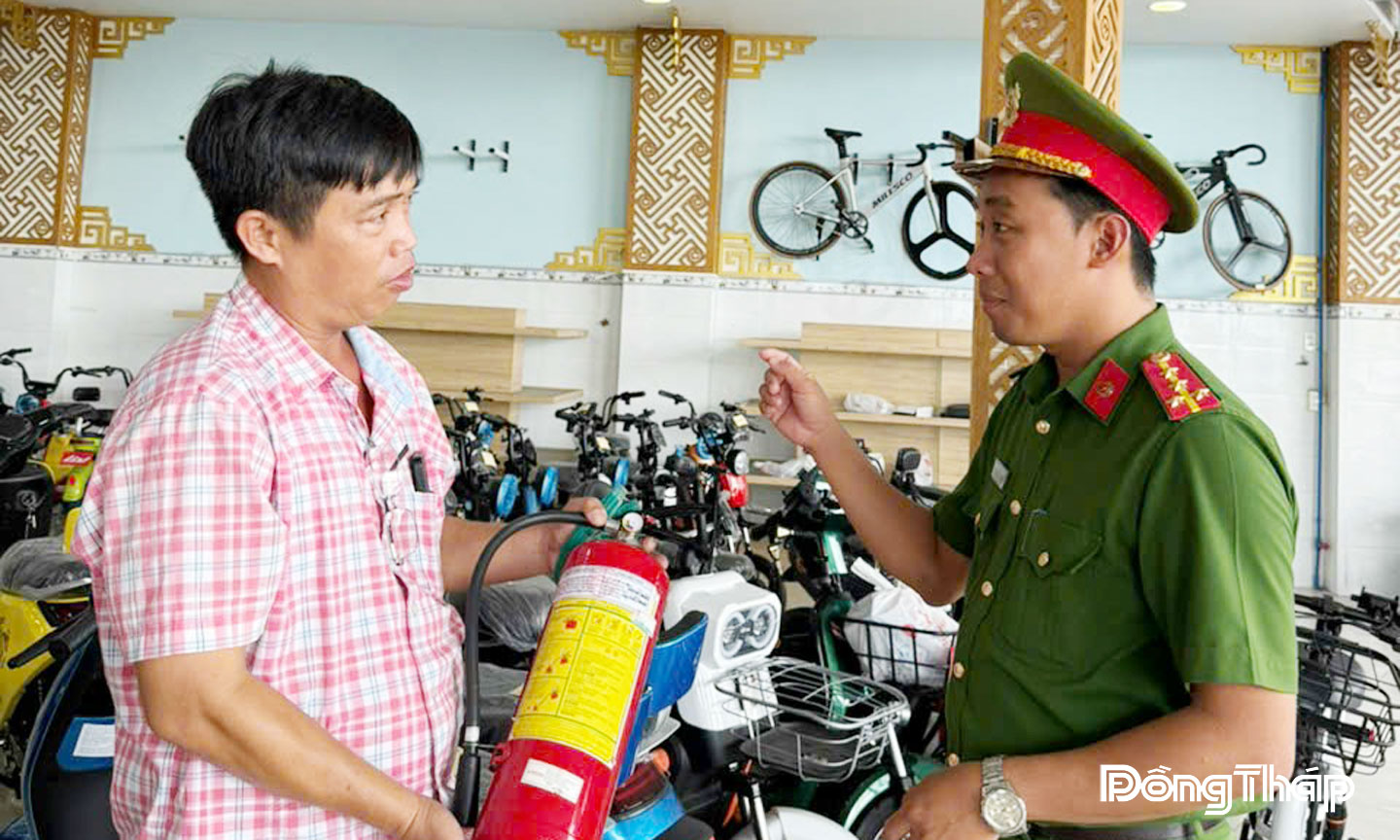 Lực lượng Công an tuyên truyền về phòng cháy, chữa cháy với chủ cửa hàng kinh doanh xe máy điện.