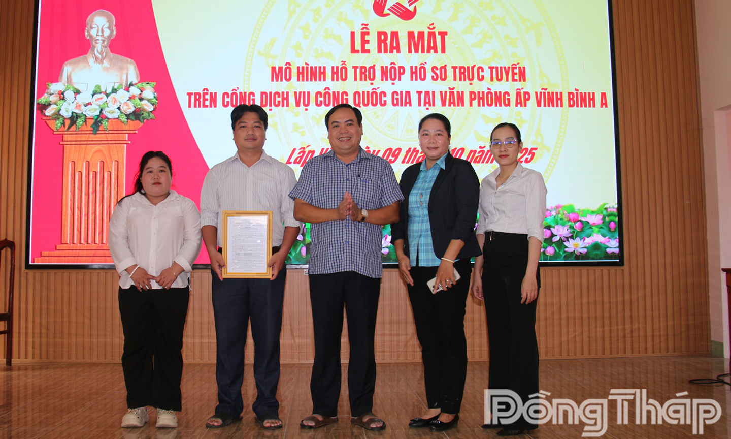 Ông Trần Hoàng Nam, Chủ tịch UBND xã Lấp Vò (đứng giữa) trao quyết định ra mắt Thí điểm mô hình “Hỗ trợ nộp hồ sơ trực tuyến trên Cổng dịch vụ công Quốc gia tại Văn phòng ấp” tại trụ sở ấp Vĩnh Bình A.