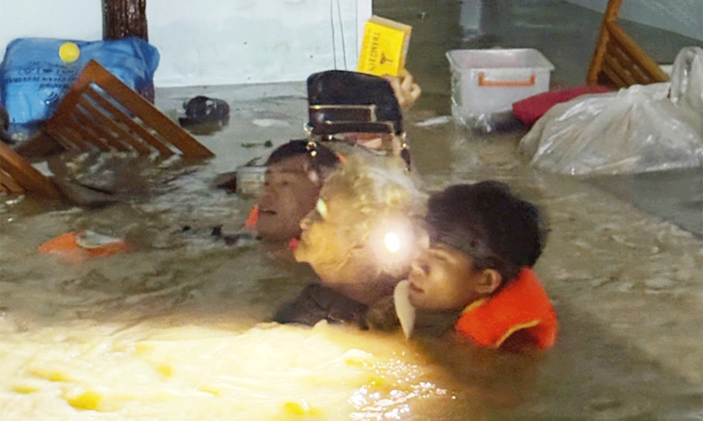 Long Nhật (đeo đèn pin) đưa cụ bà ngoài 70 tuổi ở phường Quy Nhơn Bắc, Gia Lai đến nơi an toàn, ngày 19-11. Ảnh: Lương Vĩnh Long Nhật